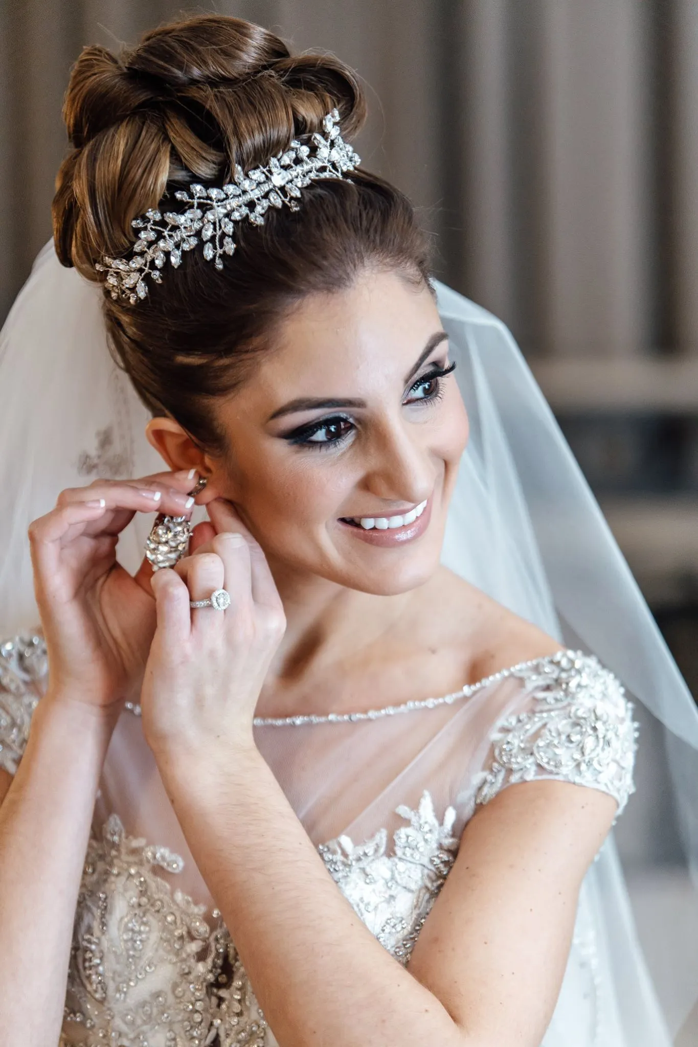 Bride with crystal leaf tiara and updo putting on earring